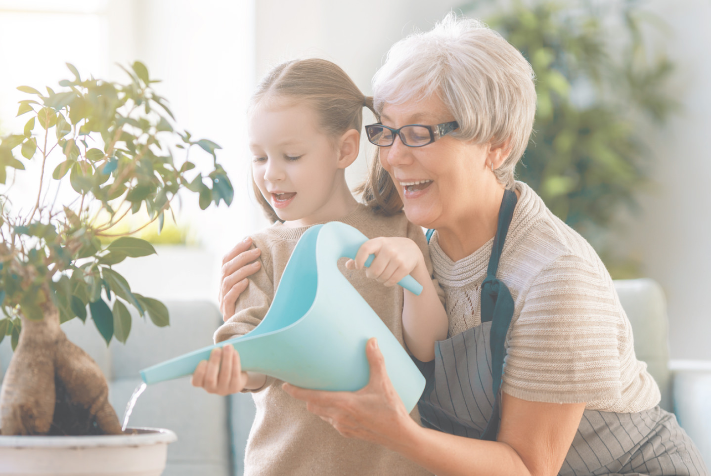 Grandmother and grandaughter watering a plant together.